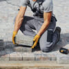 construction worker crouched down, moving a pile of bricks