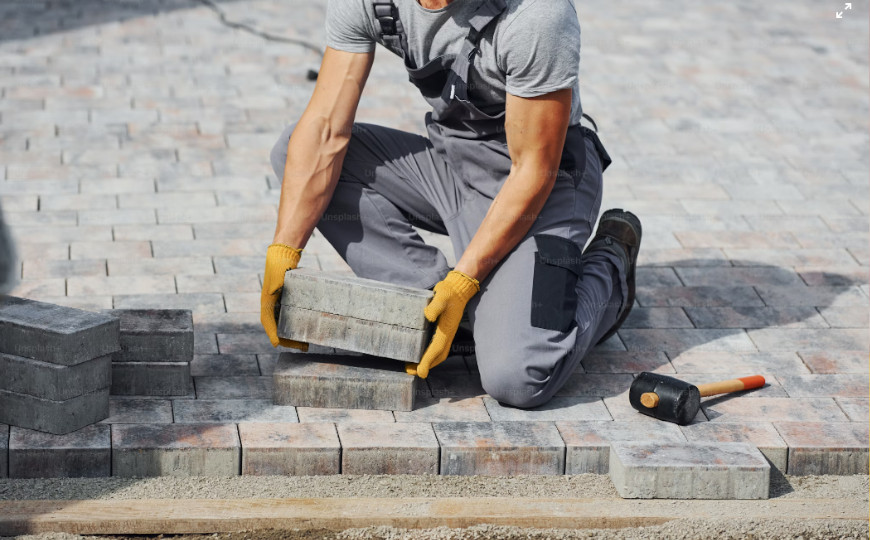 construction worker crouched down, moving a pile of bricks
